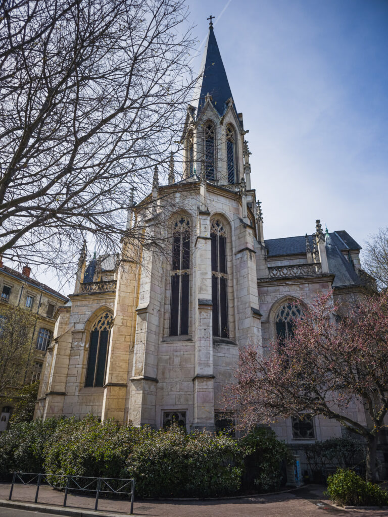 Kościół Saint-Georges w Lyonie z wysoką neogotycką wieżą otoczoną drzewami