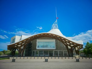 Nowoczesny budynek Centre Pompidou-Metz z charakterystyczną falującą konstrukcją dachu na tle błękitnego nieba