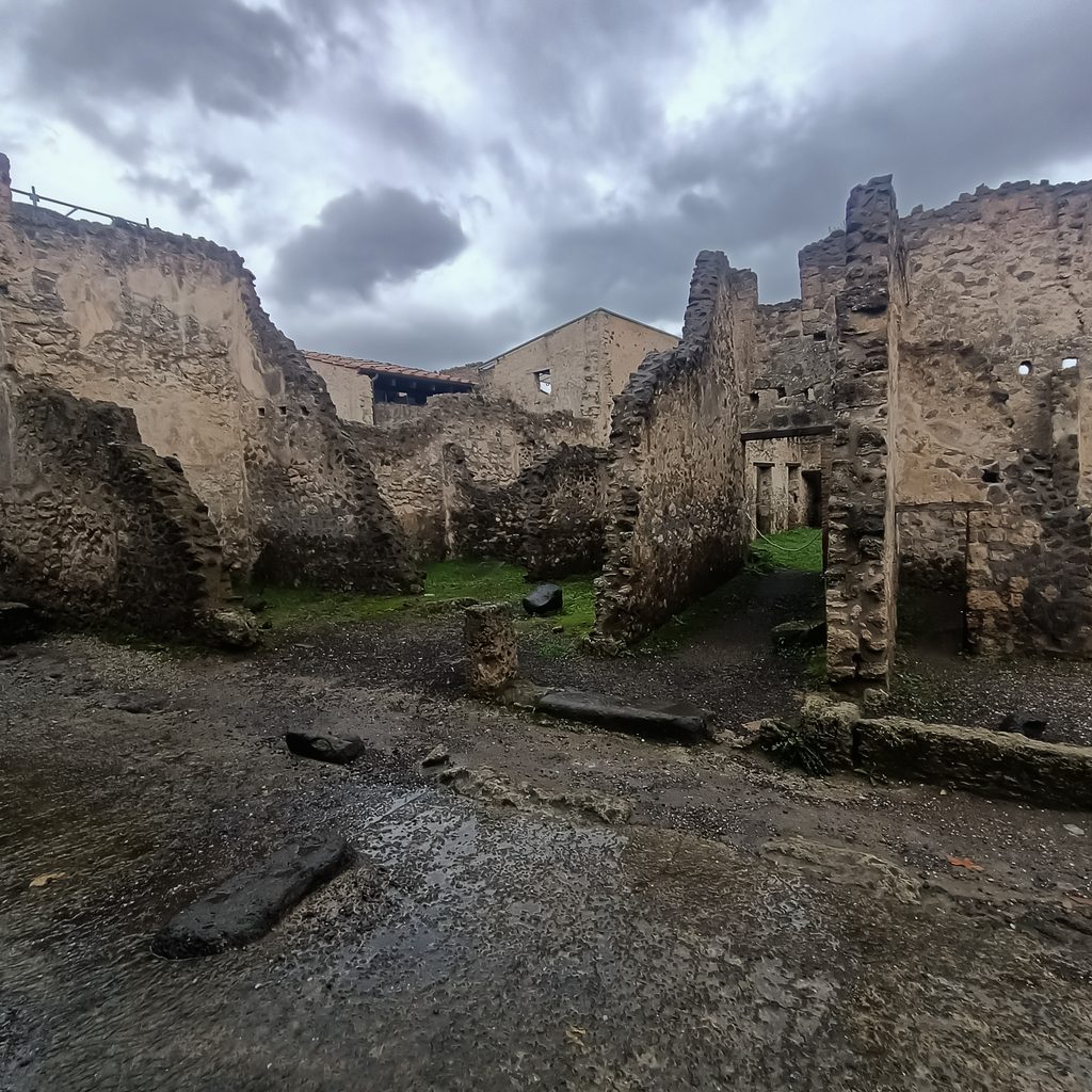 Ruiny zabudowań mieszkalnych przy mokrej ulicy w starożytnych Pompejach