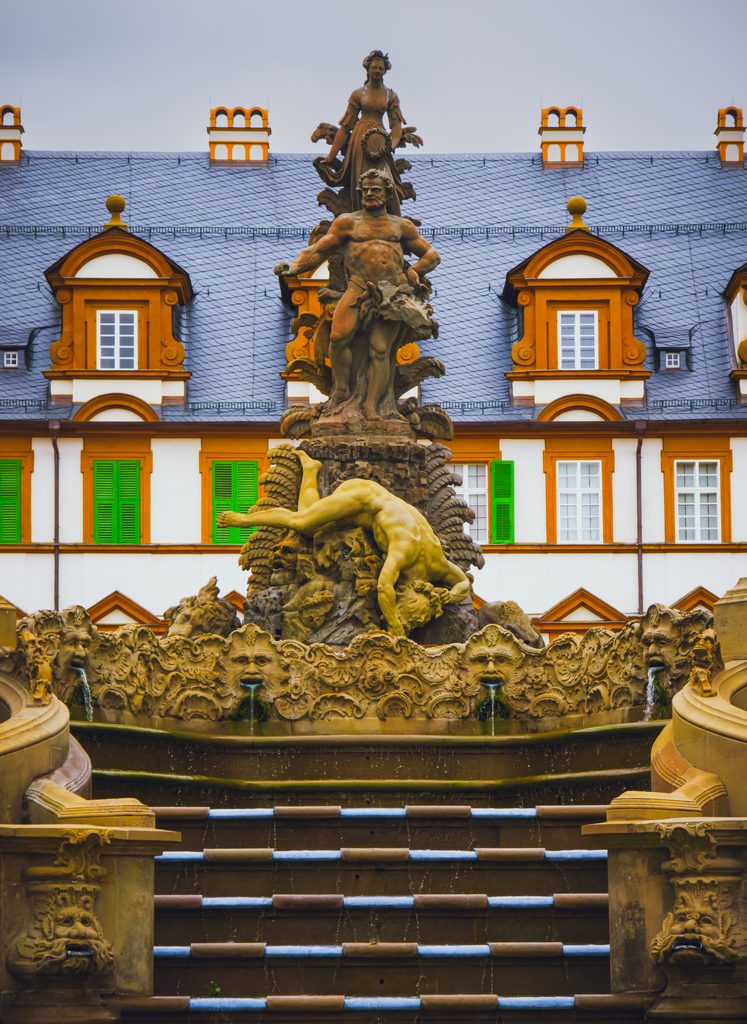 Barokowa fontanna z rzeźbami w ogrodach pałacu Seehof w Memmelsdorfie, z fasadą pałacu w tle