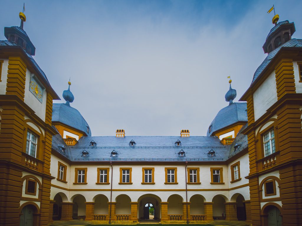 Wewnętrzny dziedziniec pałacu Seehof w Memmelsdorfie z arkadami, narożnymi wieżami i widokiem na dachy rezydencji