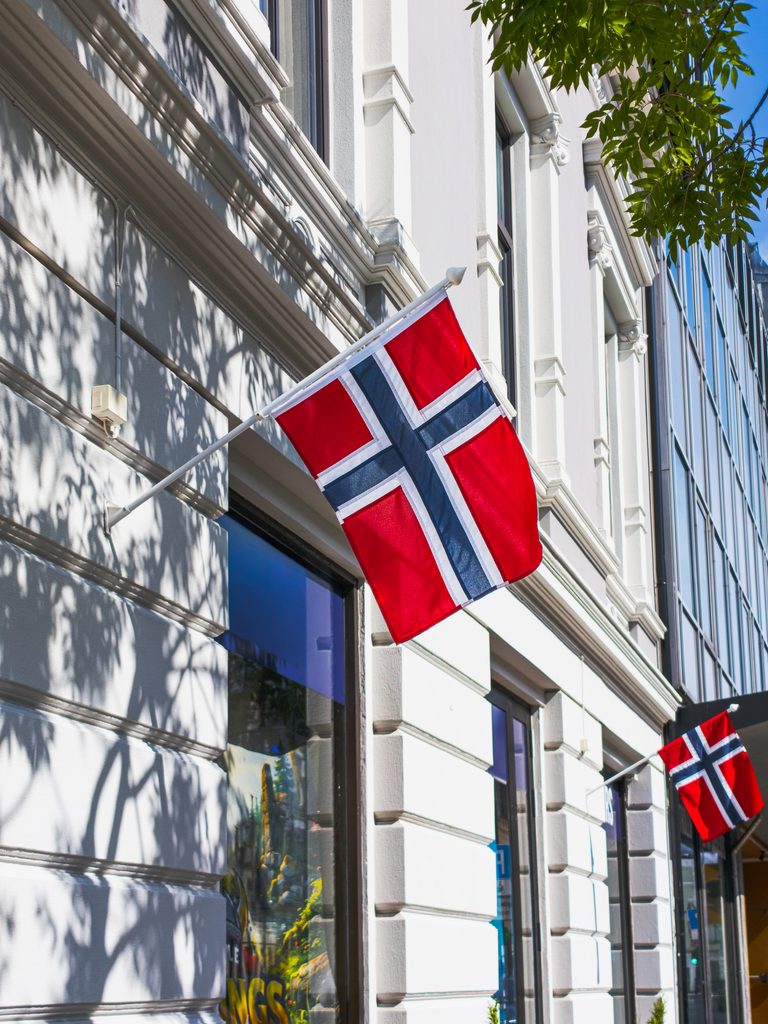 Norweskie flagi na fasadzie zabytkowej kamienicy w centrum Kristiansand, Norwegia.