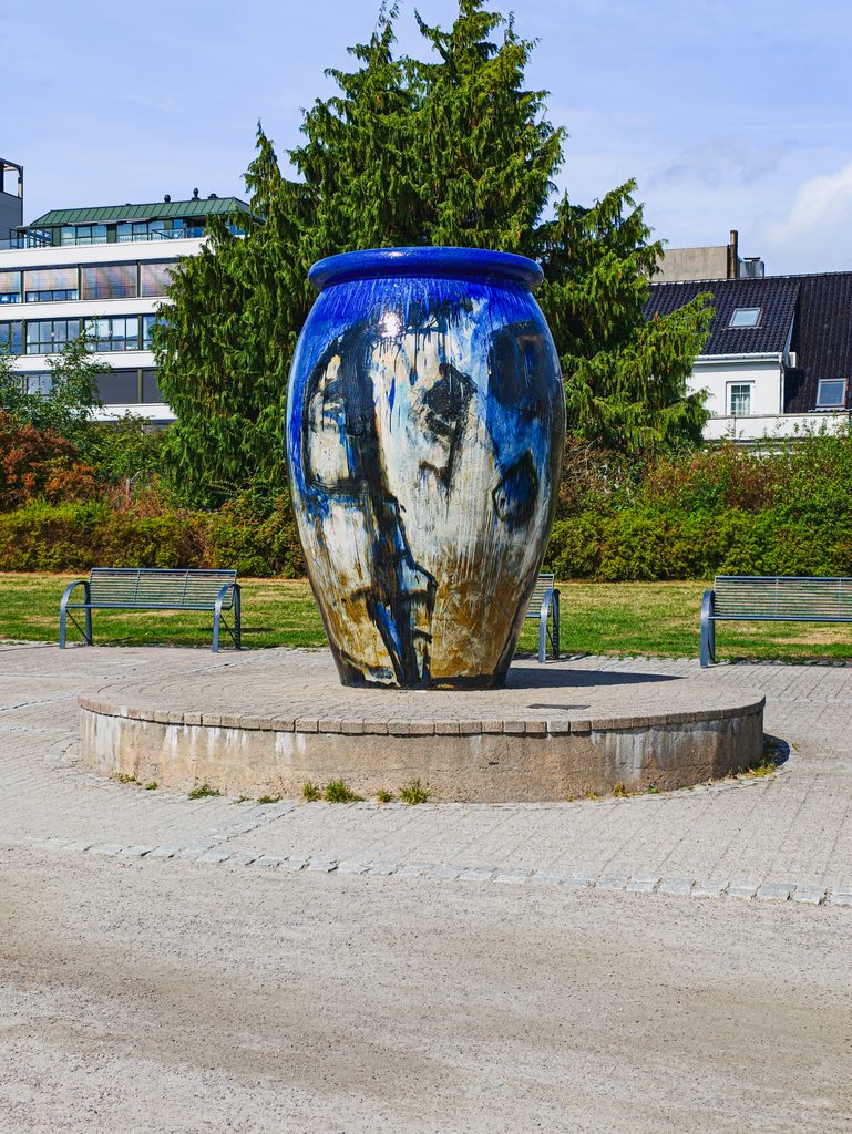 Monumentalna niebiesko-biała ceramiczna rzeźba KRUKKE TIL KRISTIANSAND w Kristiansand w Norwegii, otoczona zielenią.